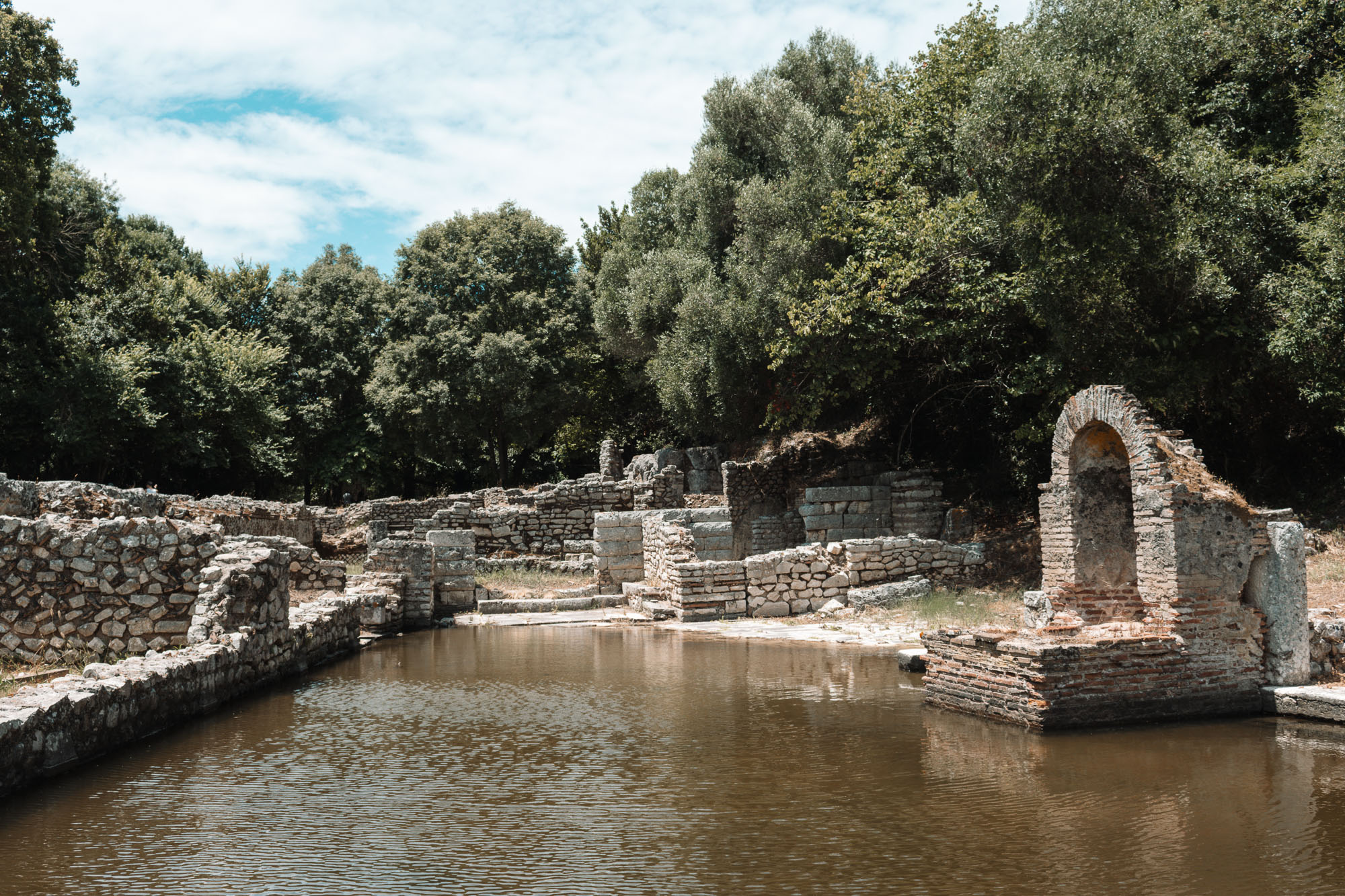 Ruinen mit gemauertem Bogen an einem überfluteten Becken in der antiken Stadt Butrint, Albanien